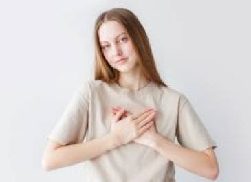 Brunette female teen holding her hands over her heart and smiling