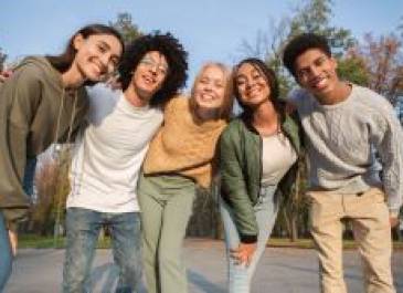 Group of teens standing with their arms over each other's shoulders and smiling.