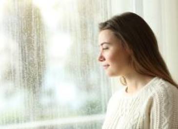 Brunette female teenager looking out of a window.