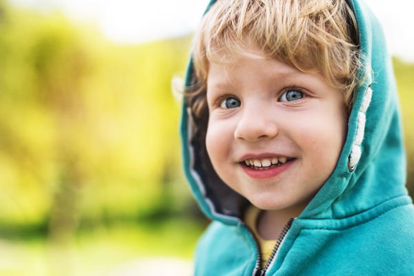 Smiling male toddler with a jacket on and a hood on his head
