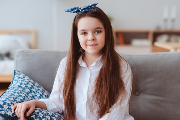 Smiling brunette child with a blue and white bow in her hair