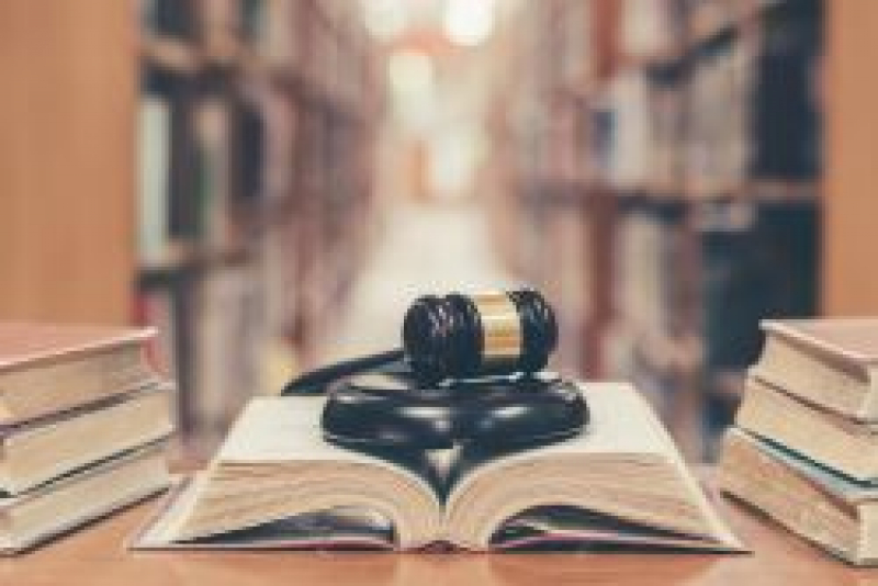 Library background with an open book and gavel on a desk.