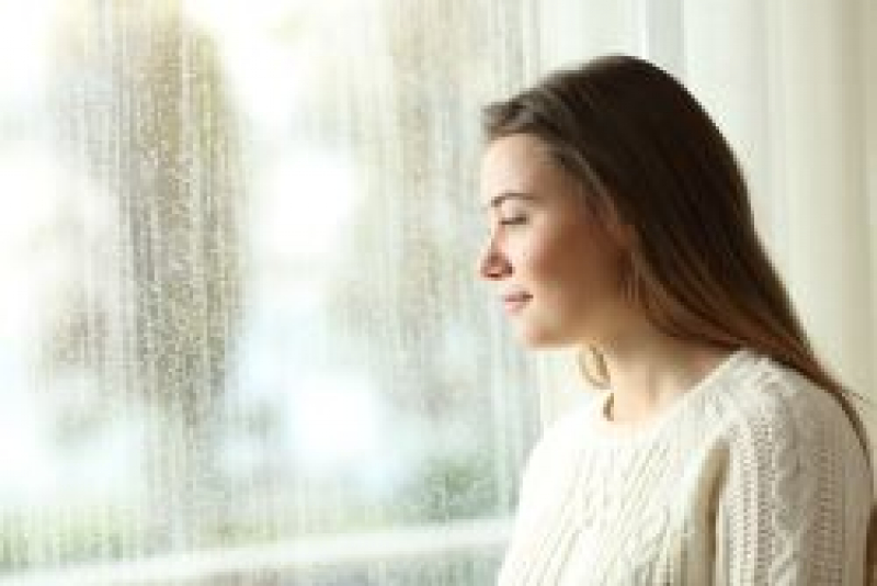 Brunette female teenager looking out of a window.