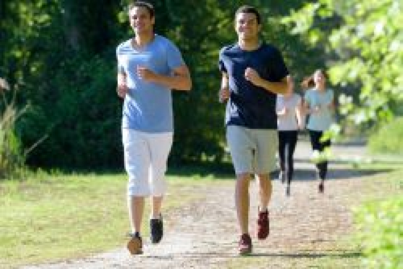 Teenage boys jogging down a dirt path.